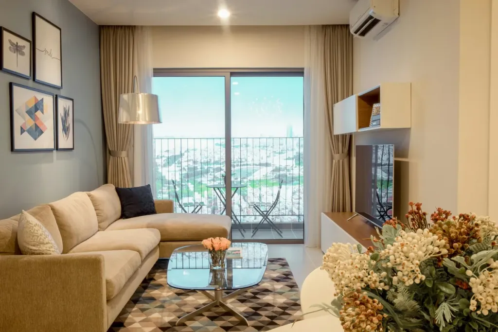 Helles Wohnzimmer mit Sofa und großer Fensterfront zum Balkon